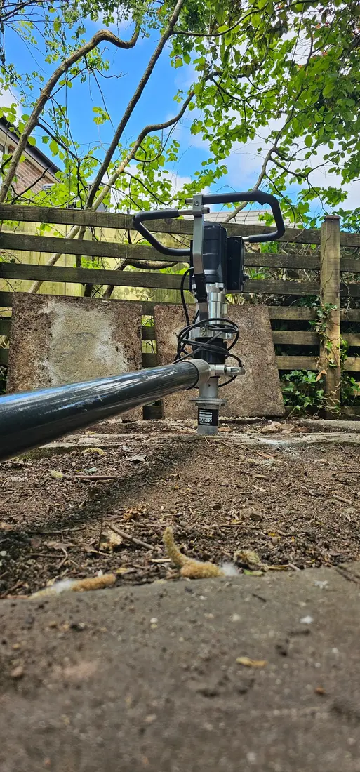 Powered ground-screw installation equipment on a residential garden site